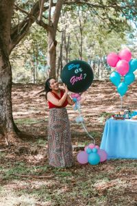 A woman holding a ‘Boy or Girl?’ balloon at a gender reveal party