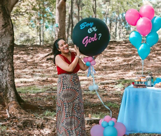 A woman holding a ‘Boy or Girl?’ balloon at a gender reveal party