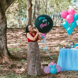 A woman holding a ‘Boy or Girl?’ balloon at a gender reveal party