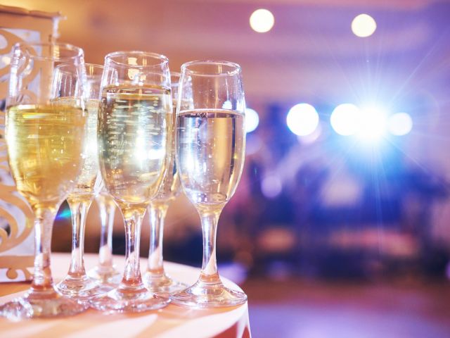 Champagne flutes filled with sparkling wine under colorful lighting at a holiday celebration.