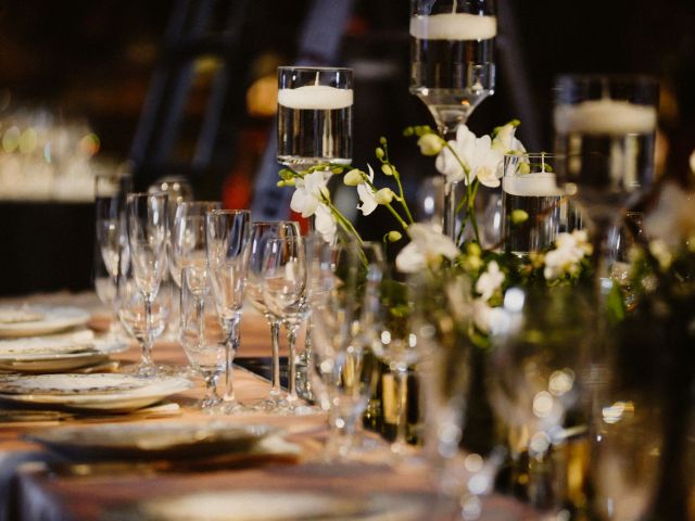 Elegant banquet table set with plates, glassware, floating candles, and white floral arrangements.